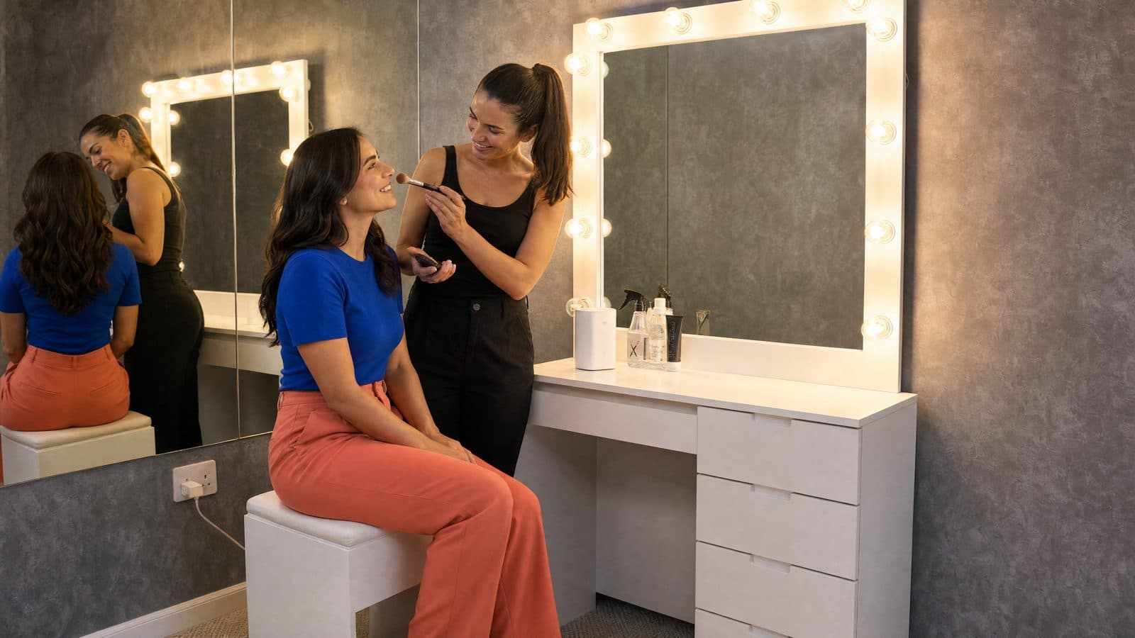 Make-up artist prepping talent at the lit mirror